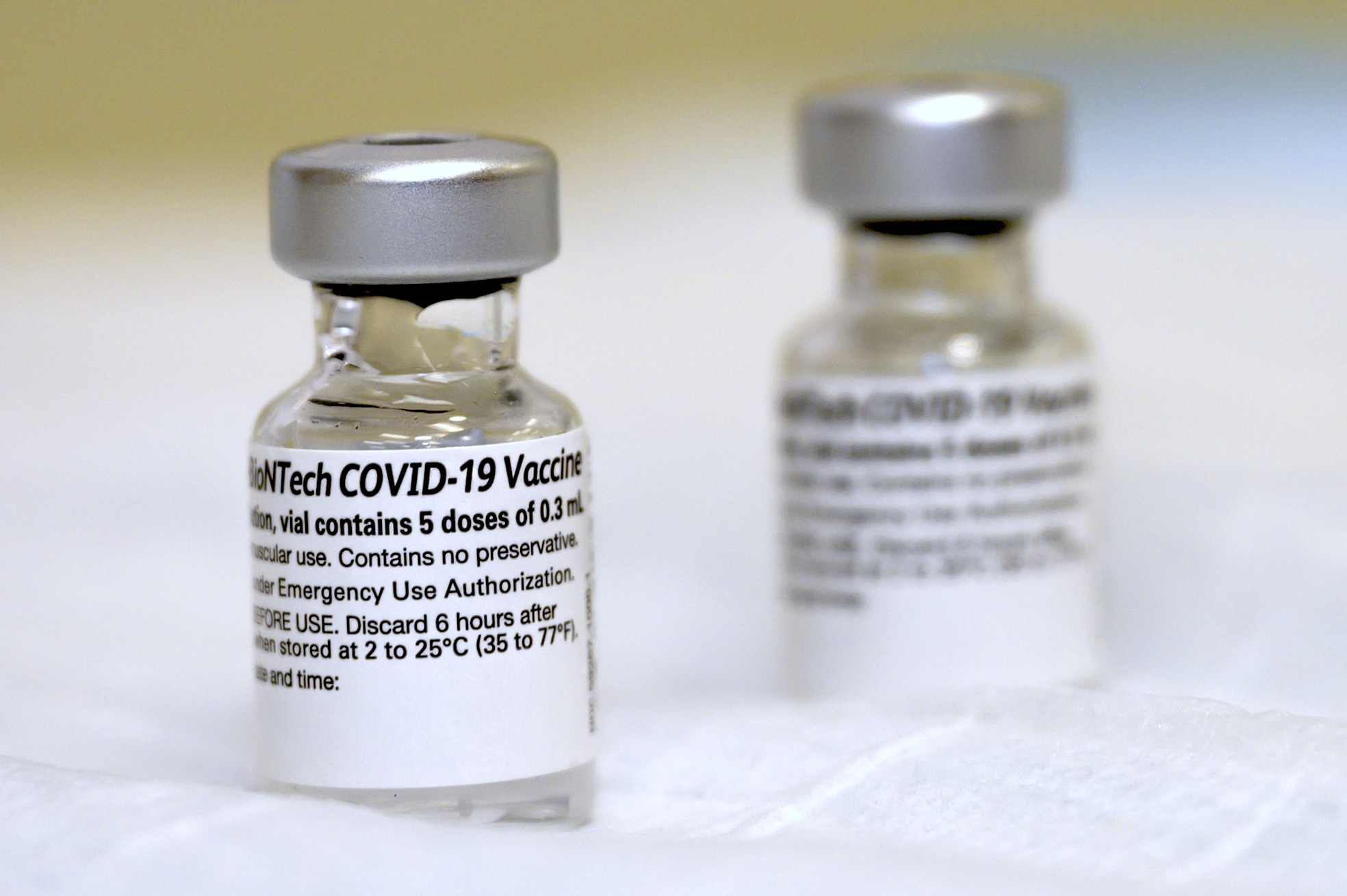 Two COVID-19 vaccine vials on a clinical surface