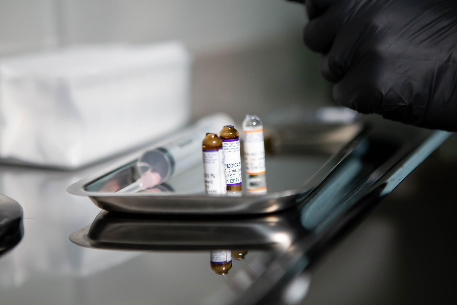 Vaccine vials and syringe on a stainless steel tray